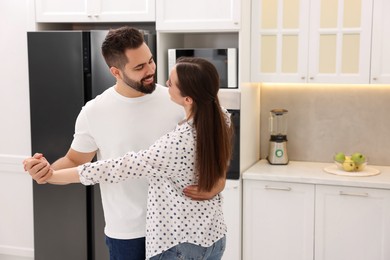 Happy lovely couple dancing together in kitchen