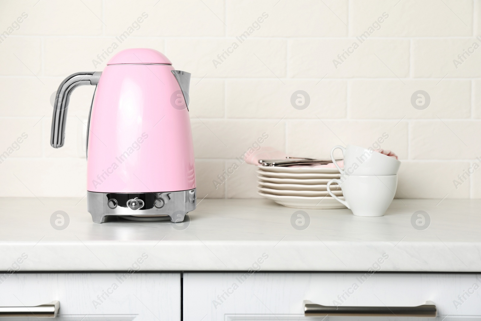 Photo of Modern electric kettle and dishes on counter in kitchen