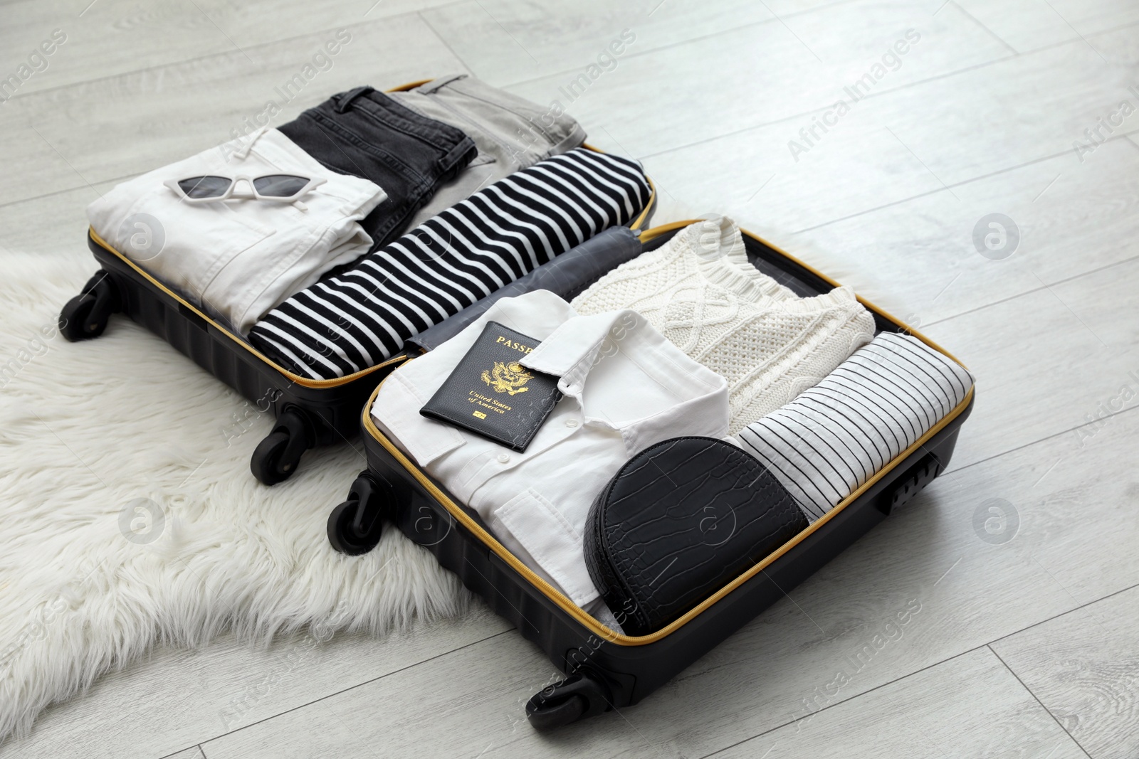 Photo of Open suitcase with clothes, passport and accessories on floor