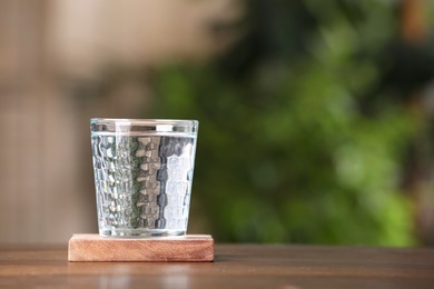 Photo of Glass of pure water on wooden table outdoors, space for text