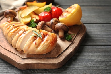 Wooden board with fried chicken breast served with garnish on table