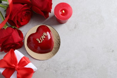 Photo of St. Valentine's Day. Delicious heart shaped cake, gift, roses and candle on light table, flat lay. Space for text