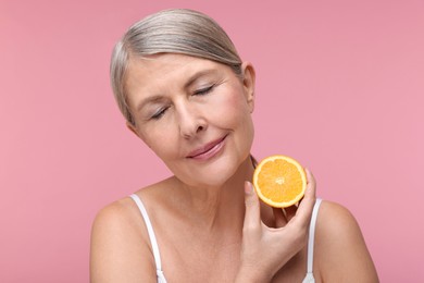 Photo of Beautiful woman with half of orange rich in vitamin C on pink background