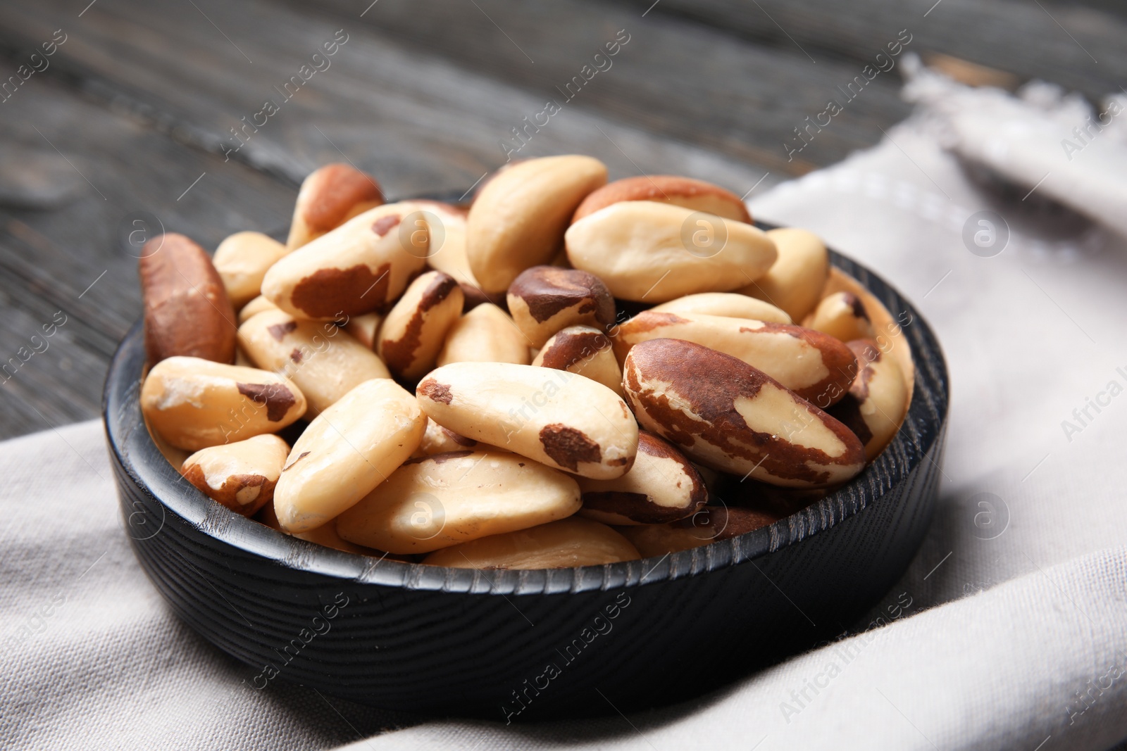 Photo of Plate with tasty Brazil nuts and fabric on table