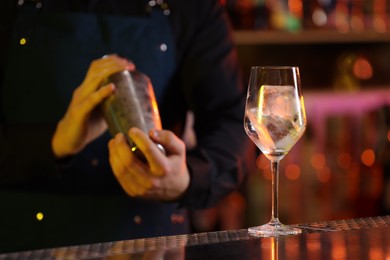 Bartender making fresh alcoholic cocktail at bar counter, selective focus
