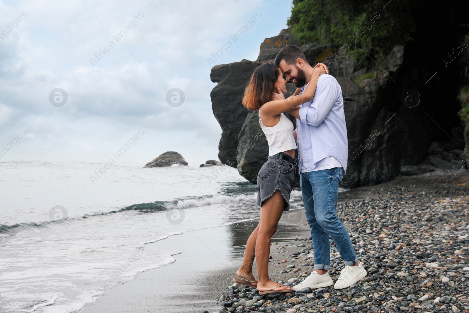 Photo of Happy young couple on beach near sea. Space for text