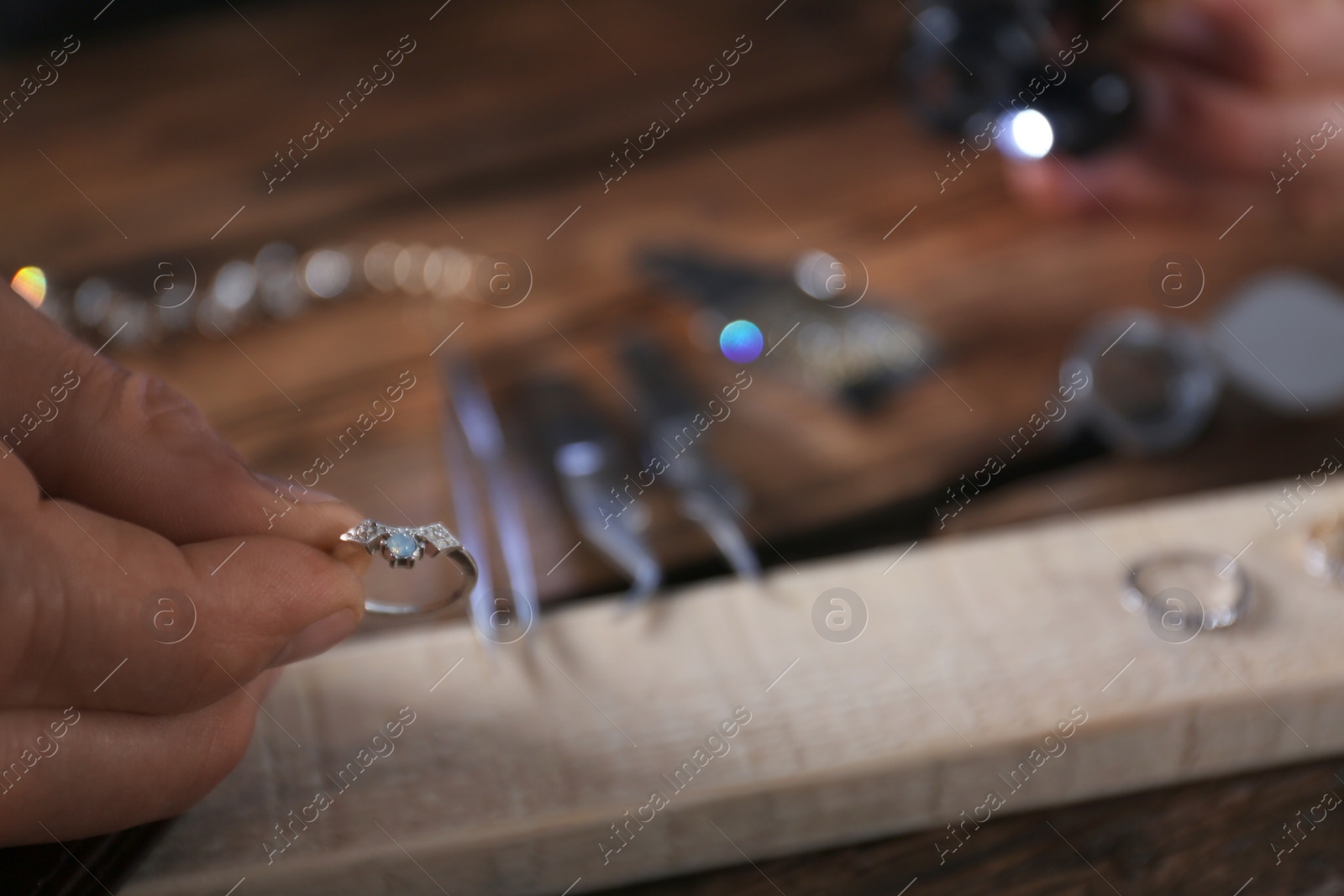 Photo of Male jeweler examining diamond ring in workshop, closeup view