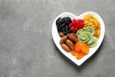Plate of different dried fruits on grey background, top view with space for text. Healthy lifestyle