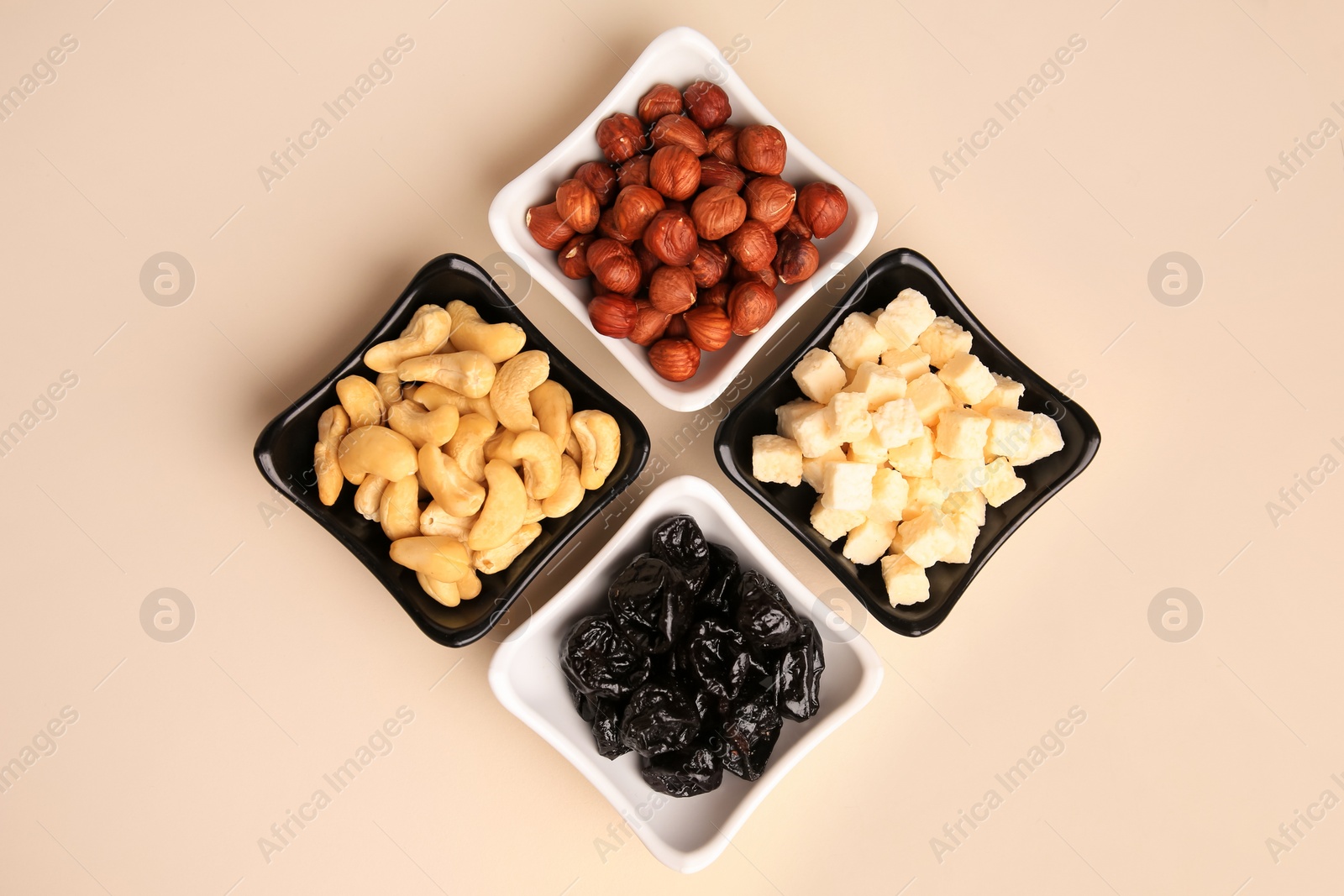 Photo of Bowls with dried fruits and nuts on beige background, flat lay