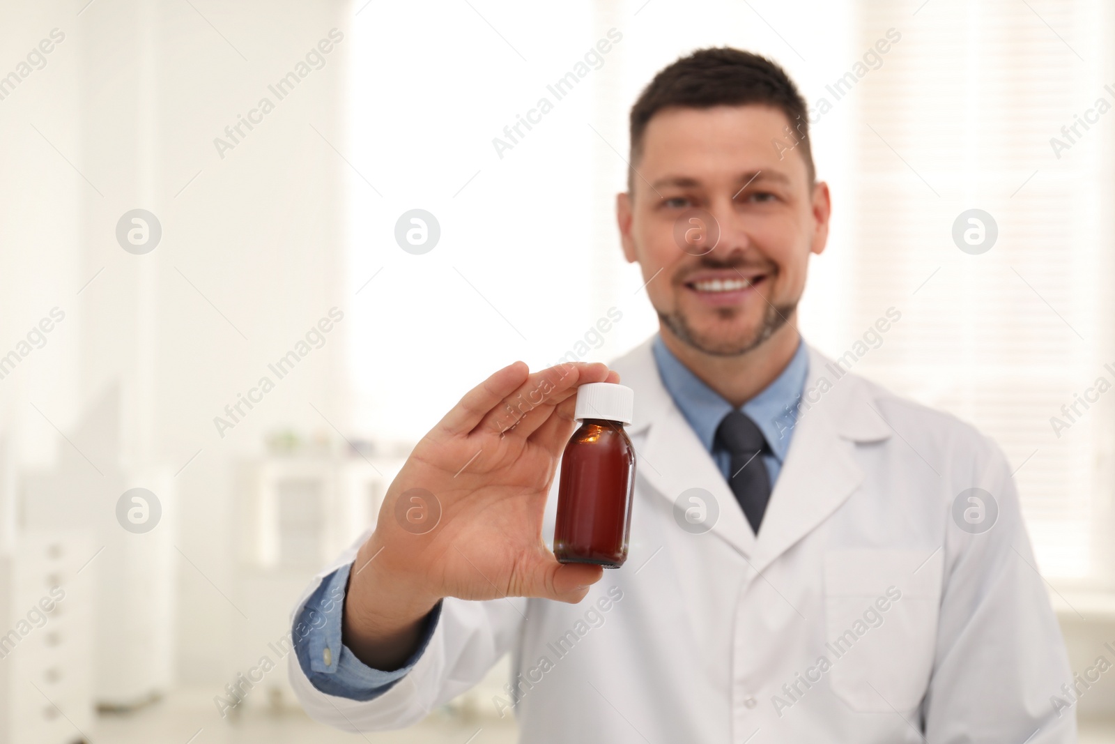 Photo of Professional pharmacist in drugstore, focus on hand with syrup
