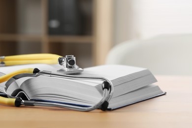 Photo of Book and stethoscope on wooden table indoors, space for text. Doctor education