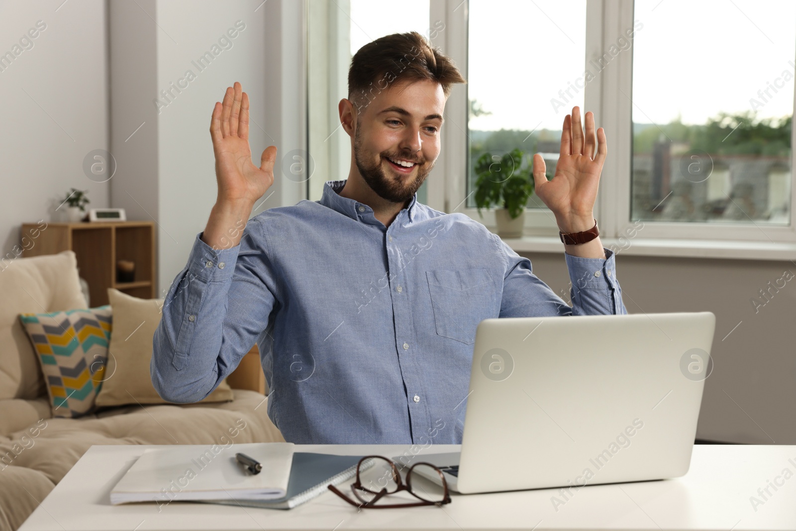 Photo of Handsome man working with laptop at table indoors