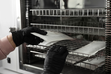 Photo of Professional manicurist putting tools into disinfection cabinet, closeup