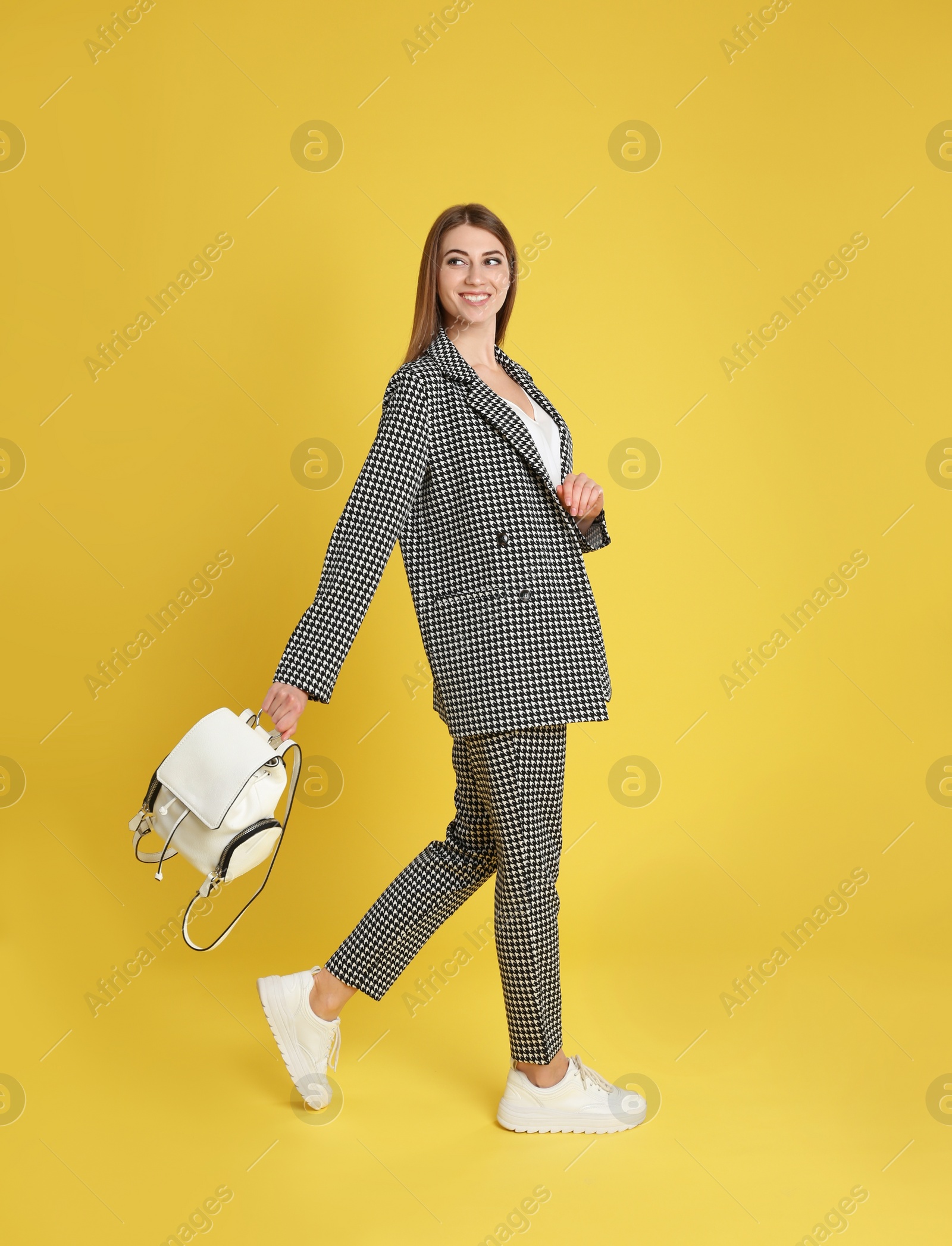 Photo of Beautiful young woman with stylish bag on yellow background