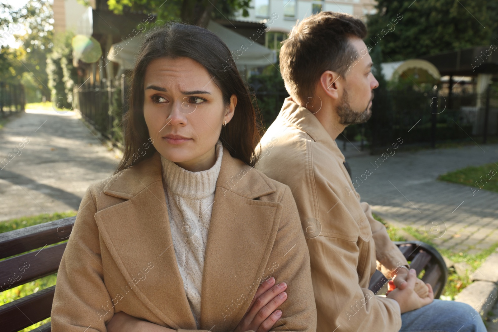 Photo of Upset arguing couple sitting on bench in park. Relationship problems