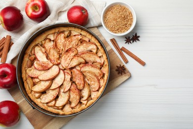 Photo of Delicious apple pie and ingredients on white wooden table, flat lay. Space for text