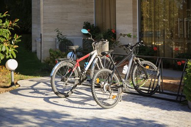 Photo of Parking rack with modern bicycles near building outdoors