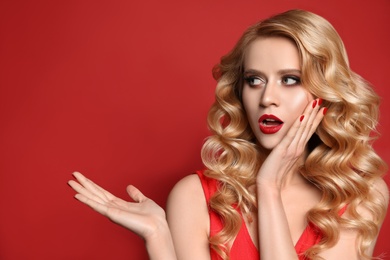 Portrait of surprised woman on red background, space for text