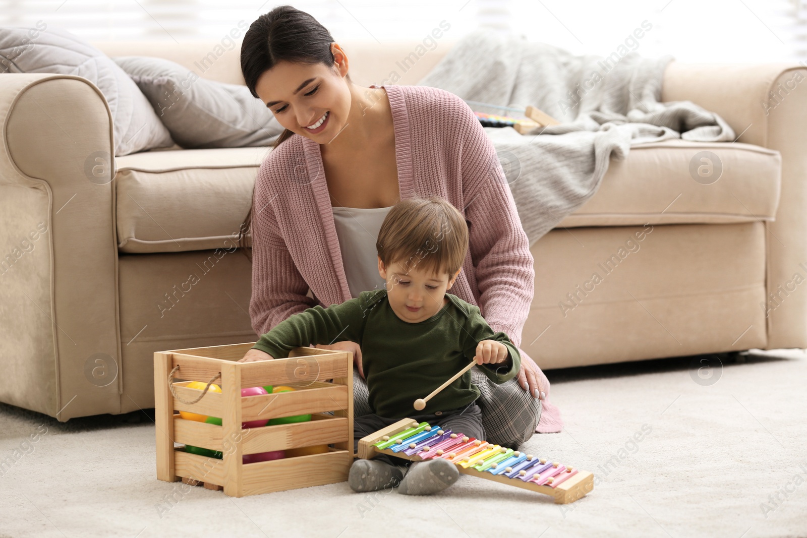 Photo of Young nanny and cute little baby playing with toys at home