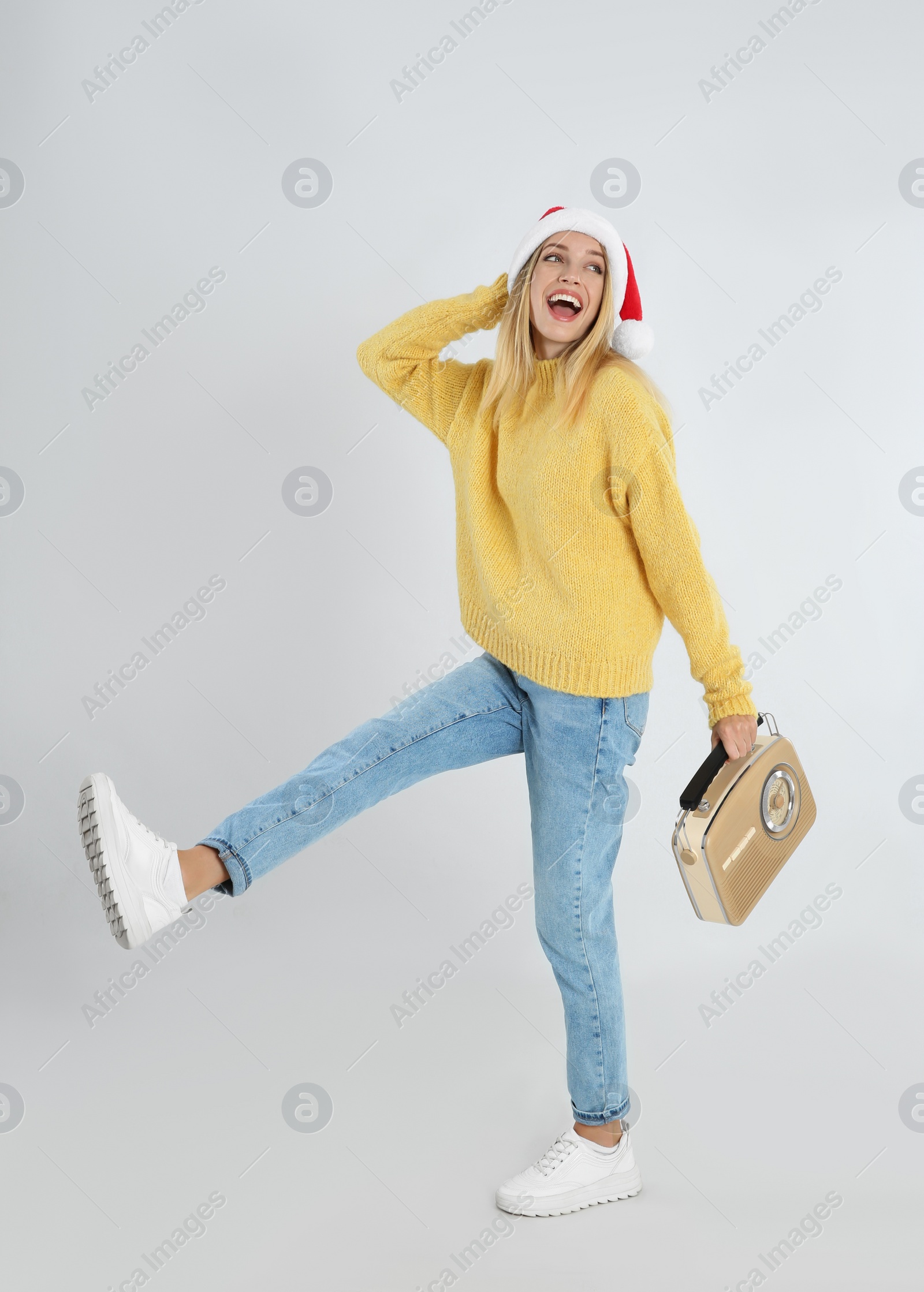 Photo of Happy woman with vintage radio on light grey background. Christmas music