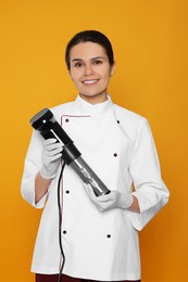 Chef holding sous vide cooker on orange background