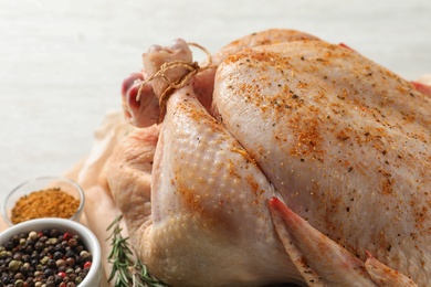Photo of Raw whole turkey with spices on table, closeup view