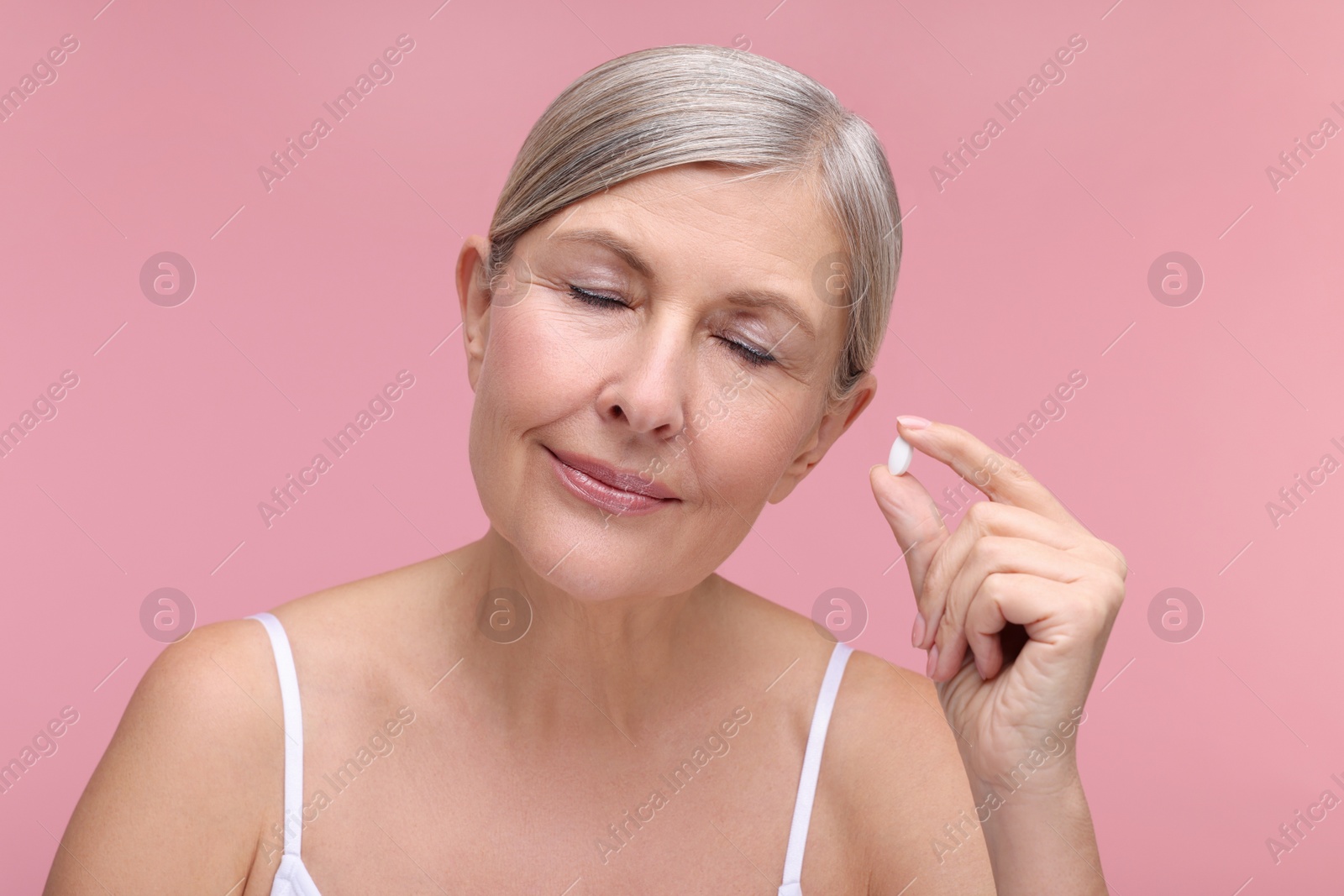 Photo of Beautiful woman with vitamin pill on pink background