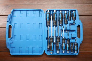 Set of screwdrivers in open toolbox on wooden table, top view