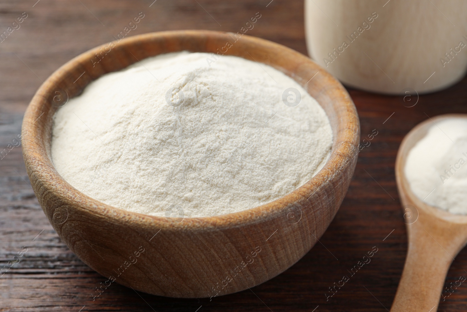 Photo of Bowl and spoon of agar-agar powder on wooden table, closeup