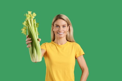 Photo of Happy woman with fresh celery bunch on green background