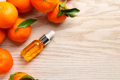 Bottle of tangerine essential oil and fresh fruits on white wooden table, flat lay. Space for text