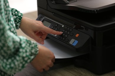 Photo of Woman using modern printer in office, closeup