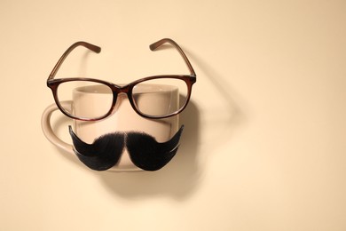 Photo of Artificial moustache, cup and glasses on beige background, top view. Space for text