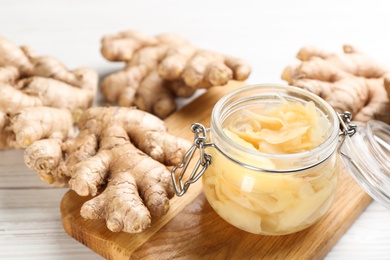 Photo of Spicy pickled ginger and root on white wooden table