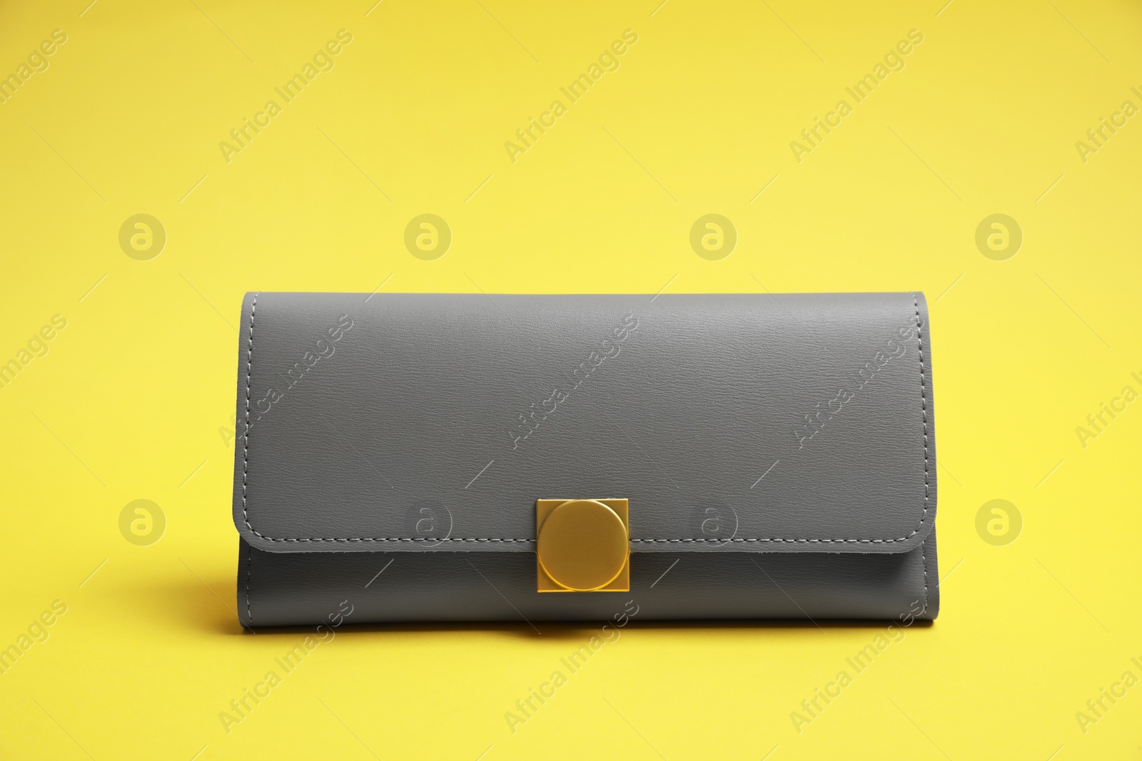 Photo of Stylish light grey leather purse on yellow background