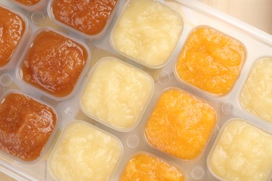 Photo of Different purees in ice cube tray, top view. Ready for freezing