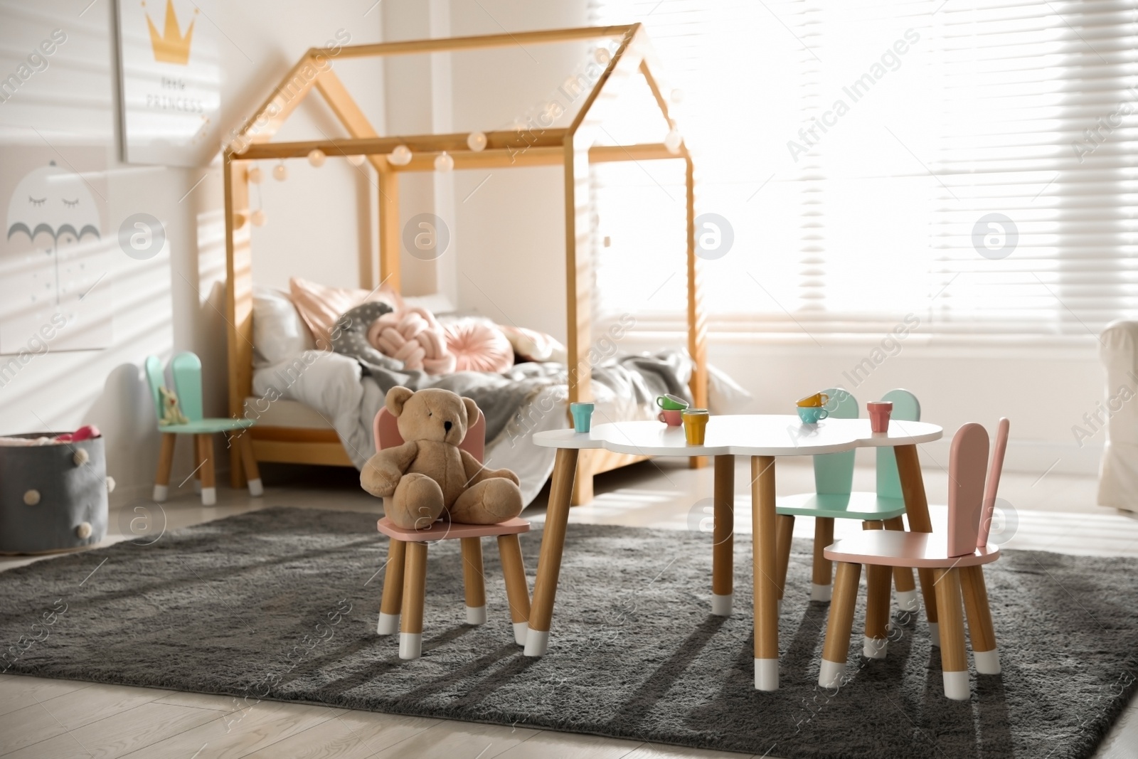 Photo of Small table and chairs with bunny ears in children's bedroom interior