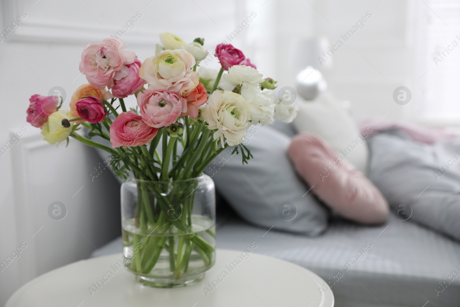 Photo of Bouquet of beautiful ranunculuses on table in bedroom. Space for text