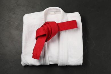 Red karate belt and white kimono on gray background, top view