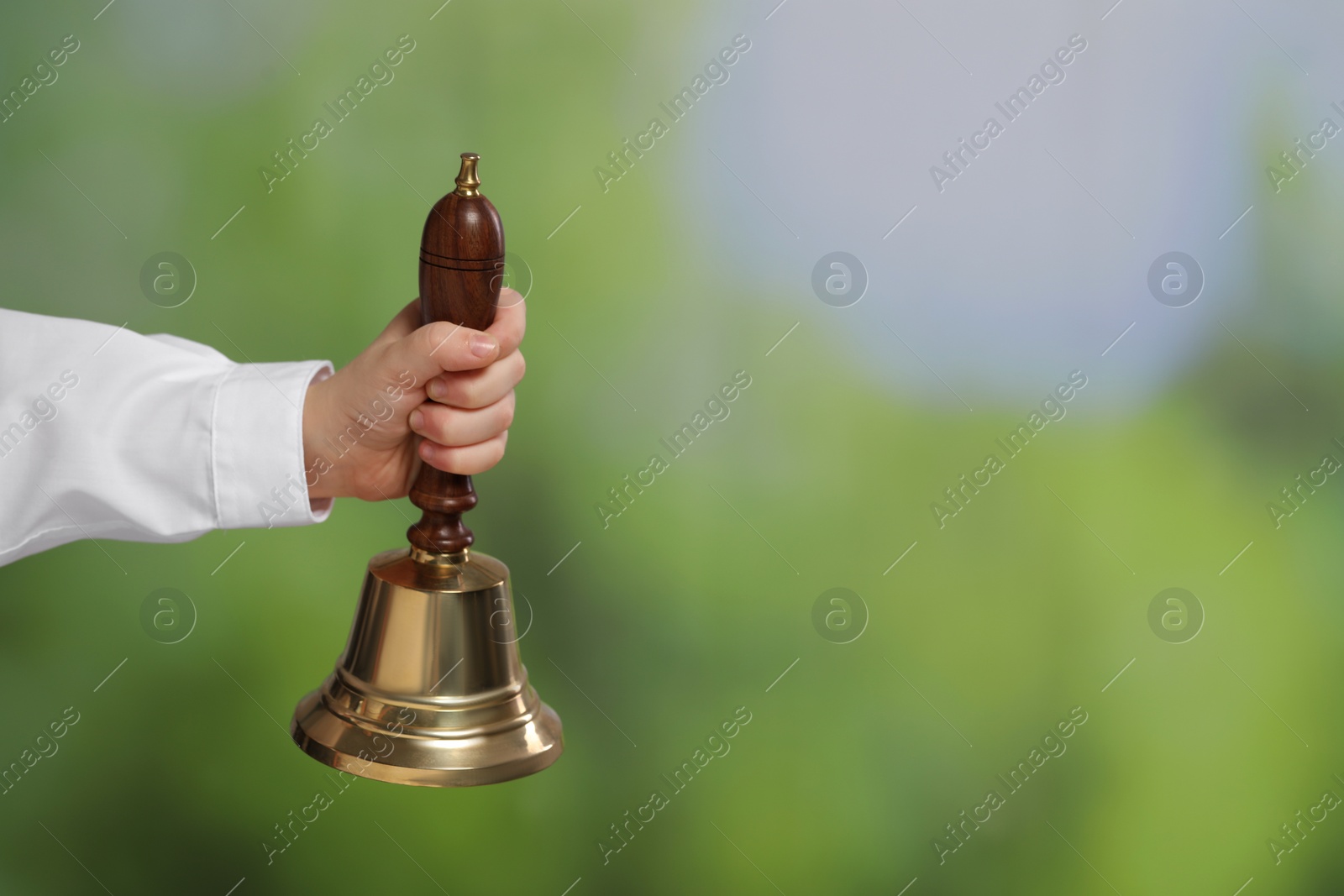 Photo of Pupil with school bell outdoors, closeup. Space for text