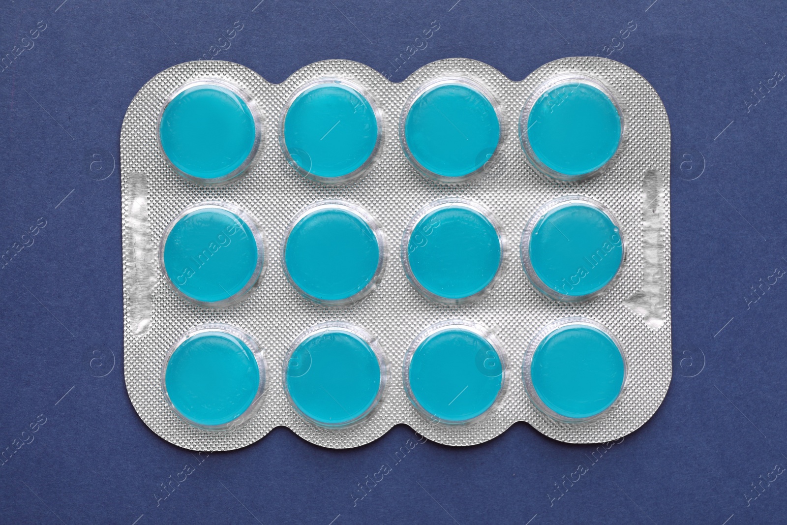 Photo of Blister with cough drops on blue background, top view