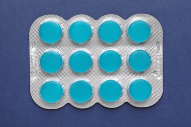 Photo of Blister with cough drops on blue background, top view