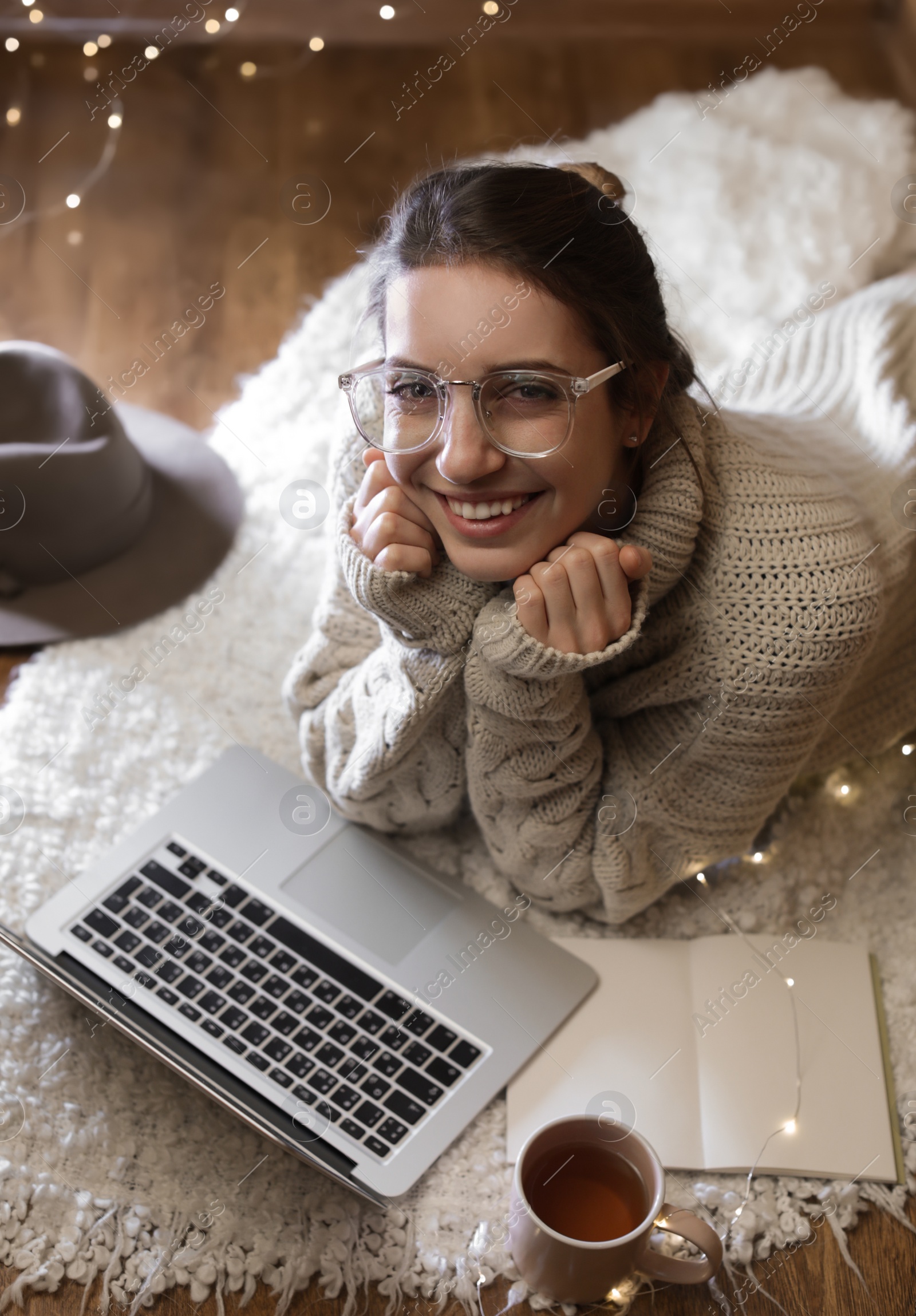 Photo of Woman with cup of hot beverage using laptop at home in winter evening