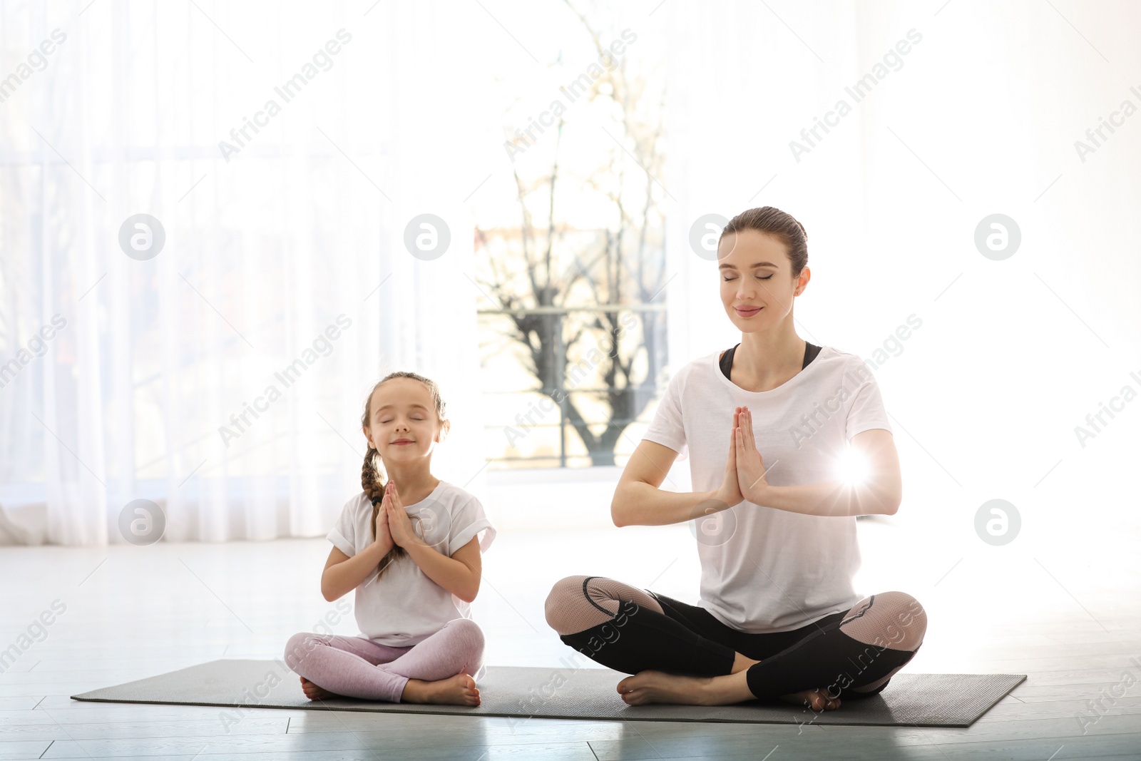 Photo of Young mother with little daughter practicing yoga at home