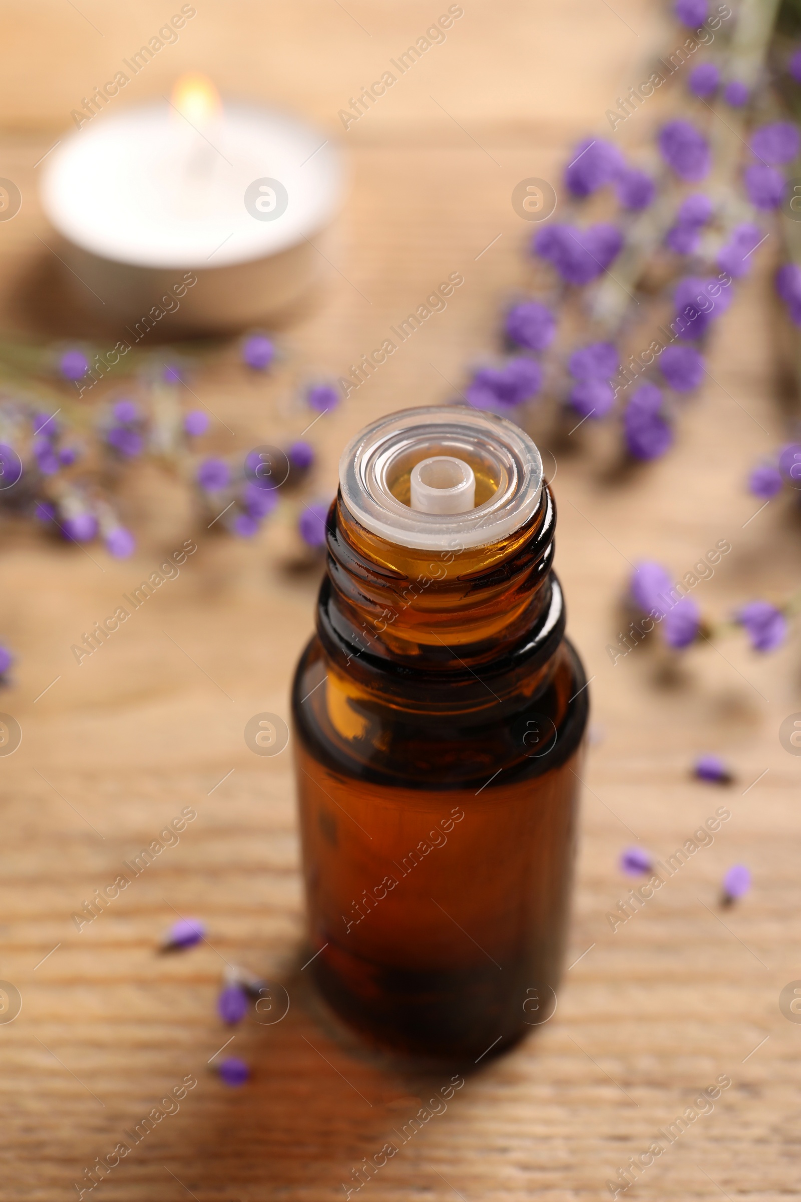 Photo of Bottle of essential oil and lavender flowers on wooden table