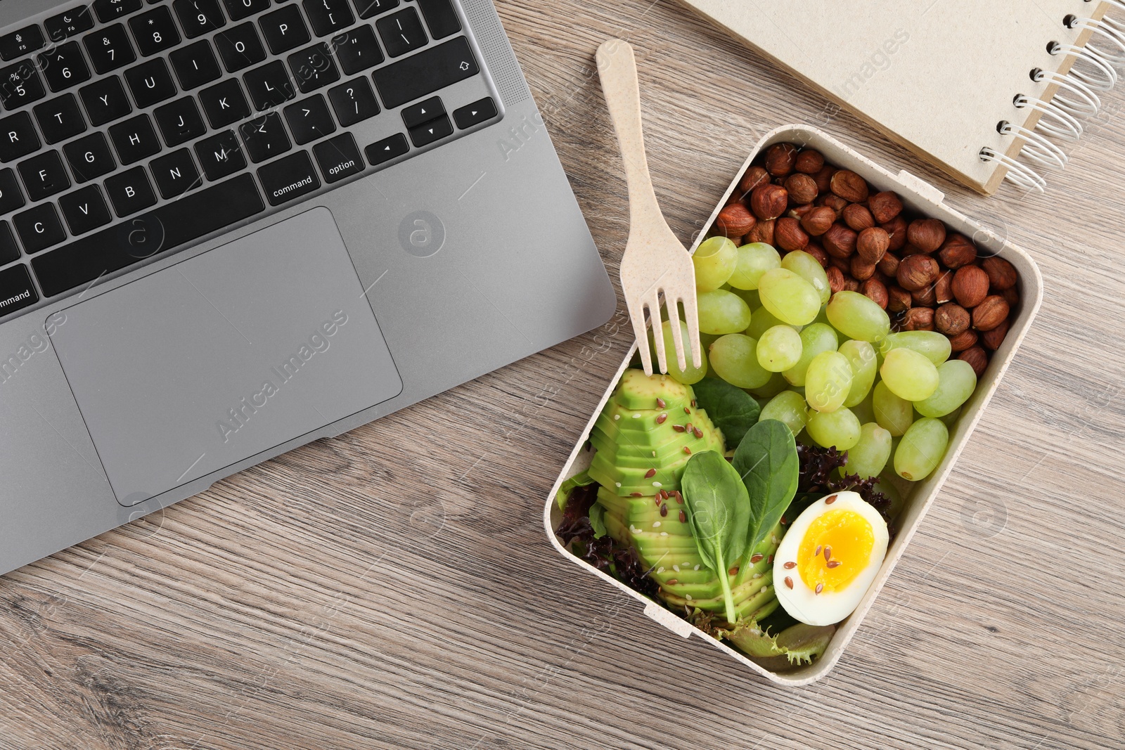 Photo of Healthy products high in vegetable fats near laptop on wooden table, flat lay