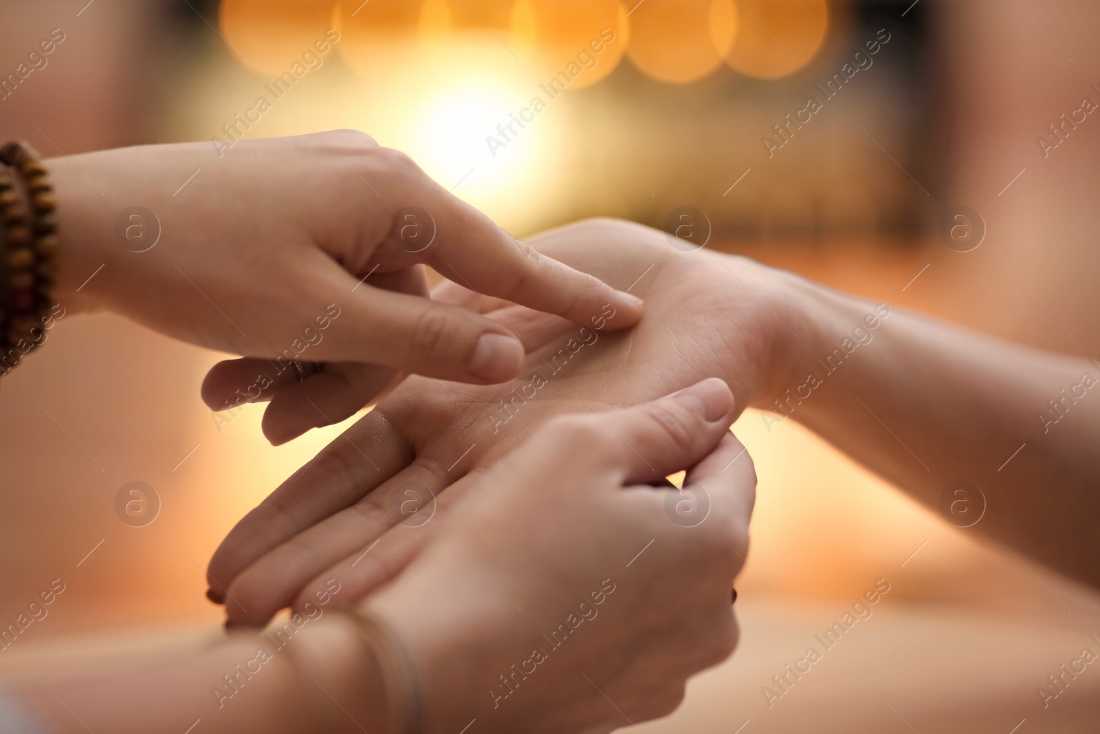 Photo of Chiromancer reading lines on woman's palm at table, closeup