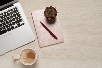 Modern laptop, houseplant, notebook and cup of coffee on wooden table, flat lay. Space for text