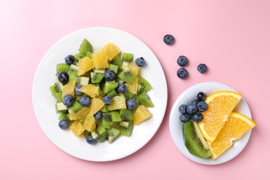 Plate of tasty fruit salad and ingredients on pink background, flat lay