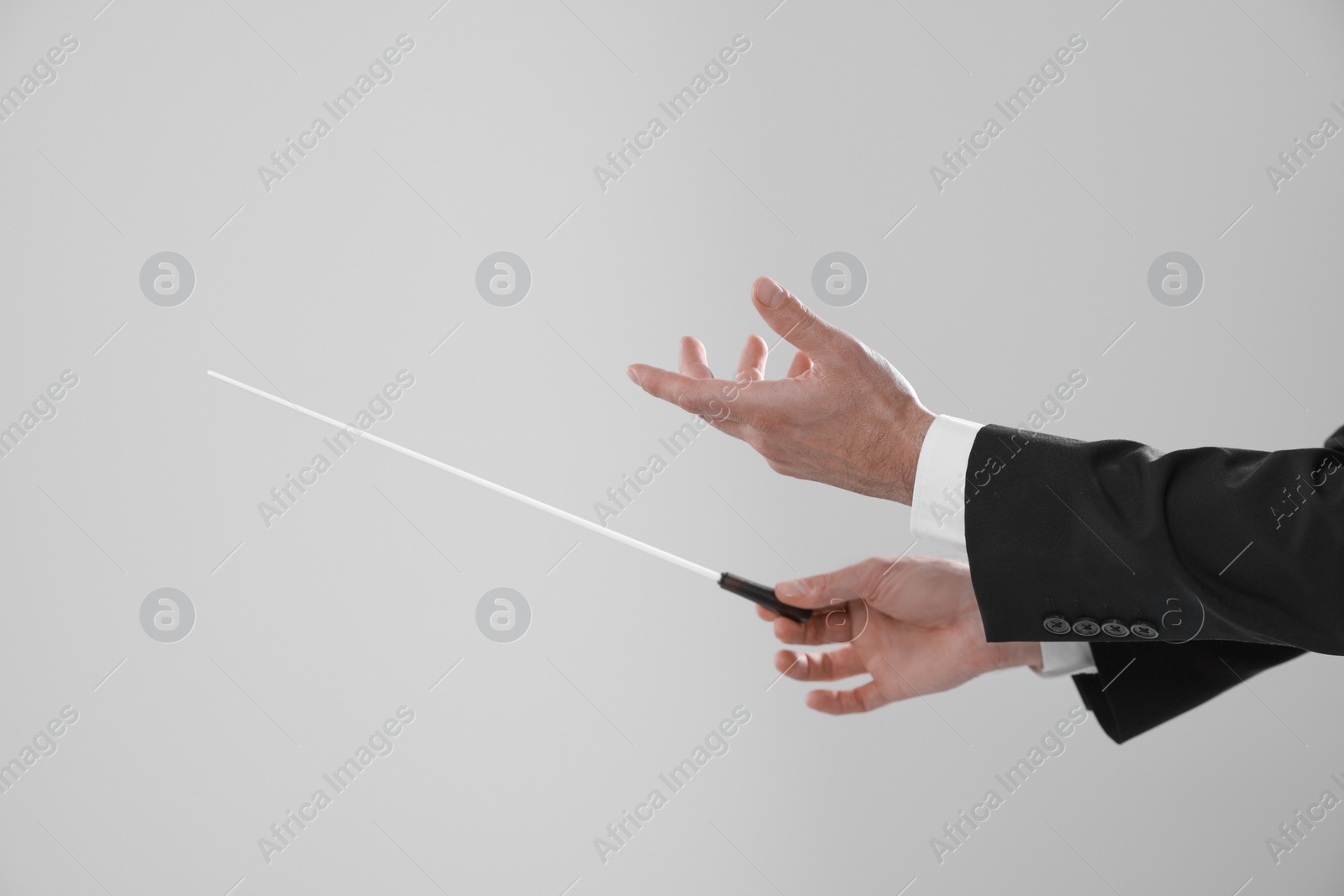 Photo of Professional conductor with baton on light grey background, closeup. Space for text